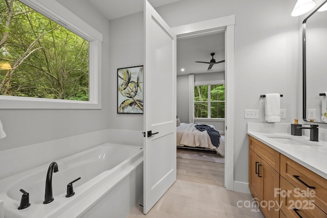 ensuite bathroom with a garden tub, ensuite bath, vanity, and plenty of natural light
