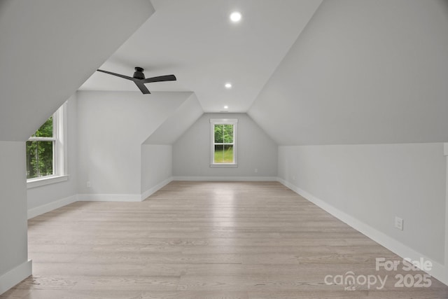 additional living space featuring baseboards, light wood-type flooring, and vaulted ceiling