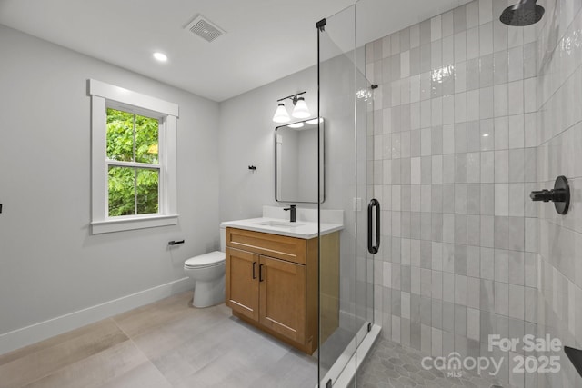 bathroom featuring toilet, vanity, baseboards, visible vents, and a stall shower
