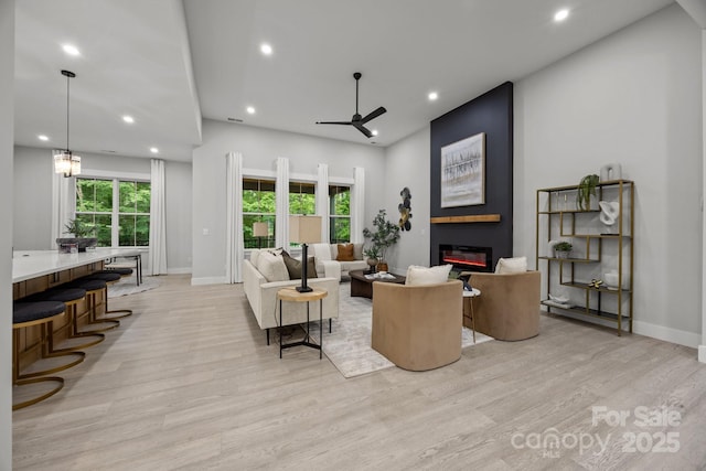 living room with a fireplace, baseboards, and light wood-style floors