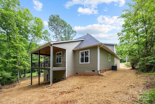 view of side of home with central AC, roof with shingles, and crawl space