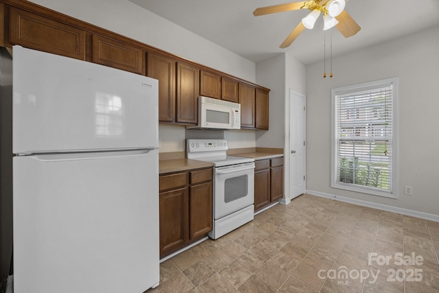 8313 Carob Tree Ln, Charlotte, NC 28215 - kitchen with white appliances, light countertops, ceiling fan, baseboards, and brown cabinetry