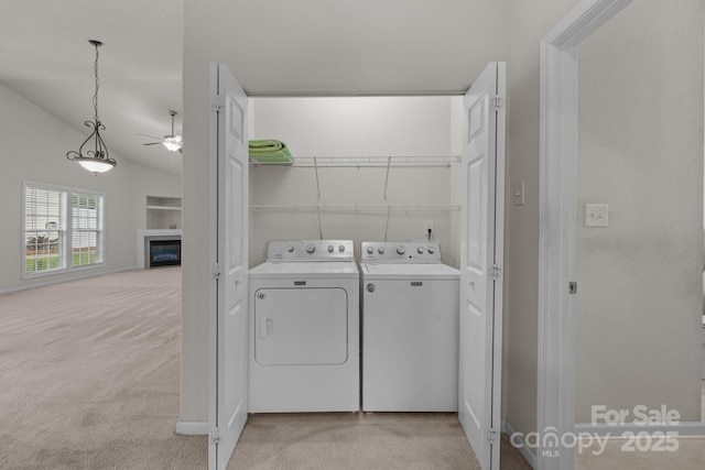 8313 Carob Tree Ln, Charlotte, NC 28215 - laundry area featuring washing machine and clothes dryer, a ceiling fan, light colored carpet, and a glass covered fireplace