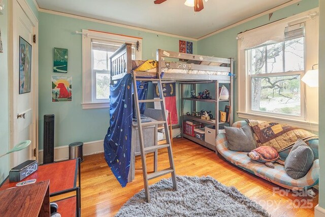bedroom with ornamental molding and wood finished floors