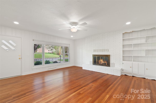 1294 Beaverdam Rd, Canton, NC 28716 - unfurnished living room with a ceiling fan, built in features, a brick fireplace, wood finished floors, and recessed lighting