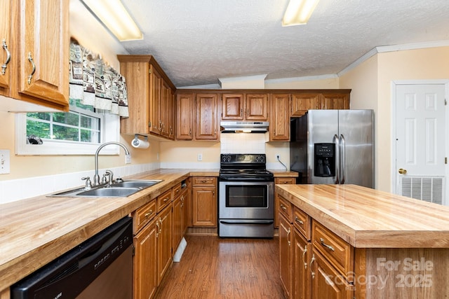 kitchen with butcher block countertops, a sink, visible vents, under cabinet range hood, and appliances with stainless steel finishes