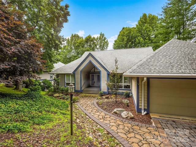 single story home featuring a shingled roof and a garage