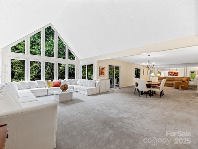 living area with high vaulted ceiling, an inviting chandelier, a healthy amount of sunlight, and light colored carpet