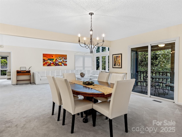 carpeted dining area featuring a textured ceiling, a healthy amount of sunlight, and a notable chandelier