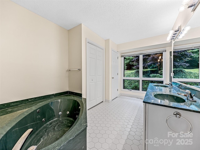 full bathroom featuring a whirlpool tub, double vanity, a textured ceiling, and a sink