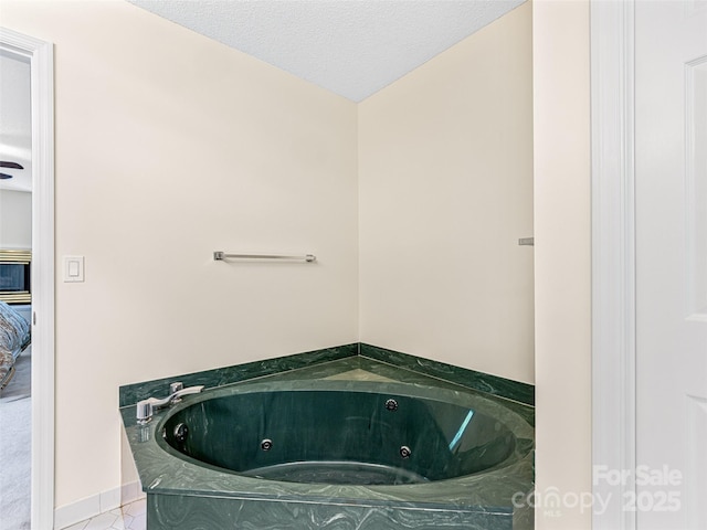 bathroom featuring a textured ceiling, tile patterned flooring, and a tub with jets