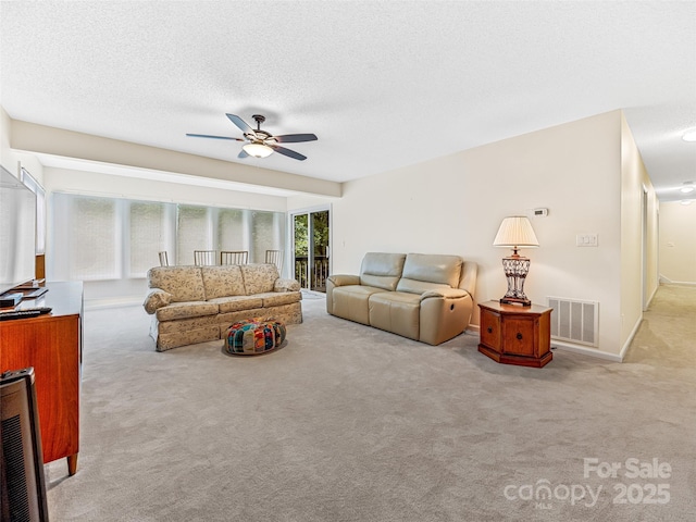 carpeted living room with visible vents, a textured ceiling, and ceiling fan