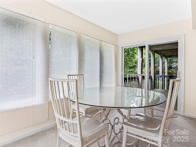 carpeted dining space featuring baseboards