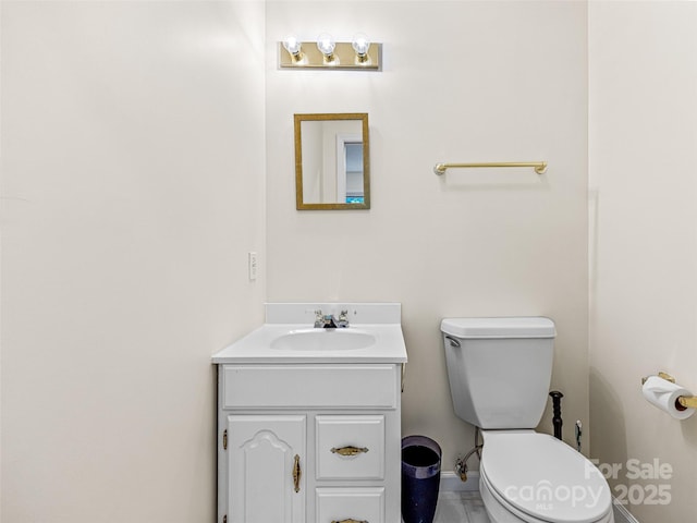 bathroom featuring baseboards, vanity, and toilet