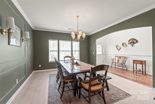 dining room featuring visible vents, ornamental molding, light wood-style flooring, and a notable chandelier