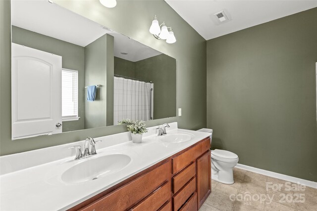 full bathroom with double vanity, toilet, baseboards, and a sink