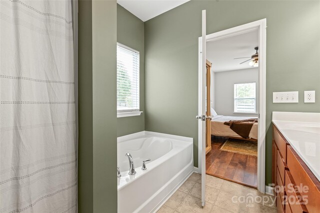 bathroom with a garden tub, a ceiling fan, plenty of natural light, and vanity