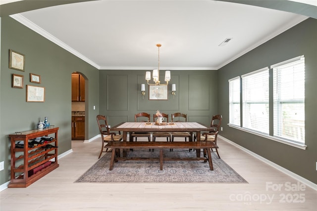 306 Fesperman Cir, Troutman, NC 28166 - dining area featuring arched walkways, ornamental molding, light wood finished floors, and a chandelier