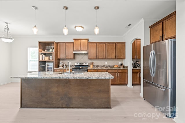 306 Fesperman Cir, Troutman, NC 28166 - kitchen featuring stainless steel appliances, crown molding, brown cabinetry, arched walkways, and backsplash