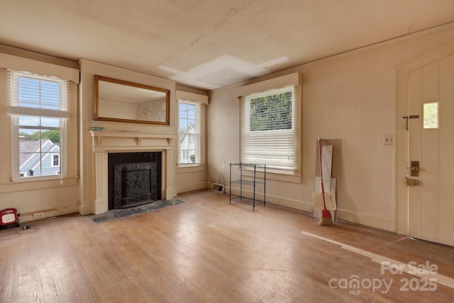 unfurnished living room with a fireplace with flush hearth, wood finished floors, and plenty of natural light