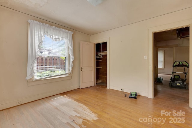 spare room with wood finished floors, a healthy amount of sunlight, and baseboards