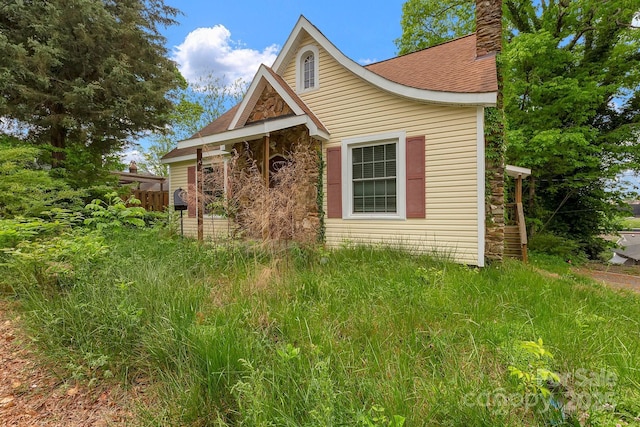 view of side of property featuring a chimney and a shingled roof