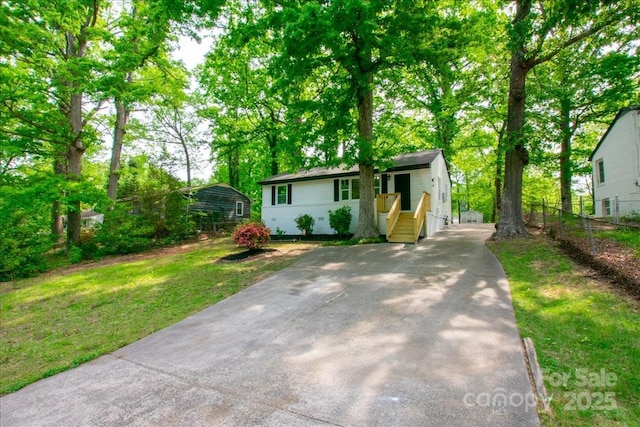 view of front facade featuring concrete driveway, a front yard, and fence