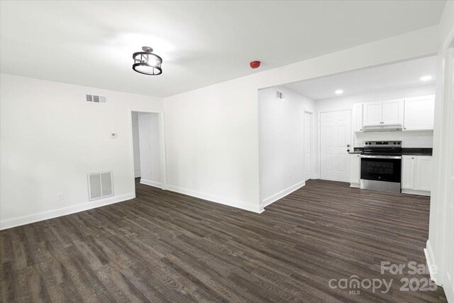 unfurnished living room with dark wood-style floors, baseboards, and visible vents
