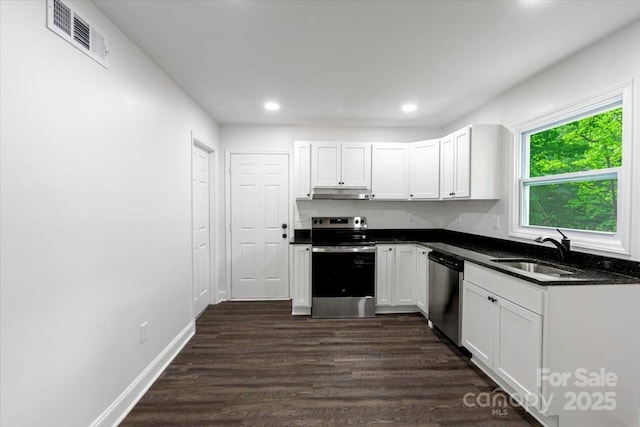 kitchen featuring under cabinet range hood, visible vents, a sink, dark wood-type flooring, and appliances with stainless steel finishes