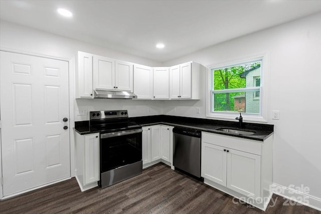 kitchen featuring dark countertops, under cabinet range hood, dark wood-type flooring, and appliances with stainless steel finishes