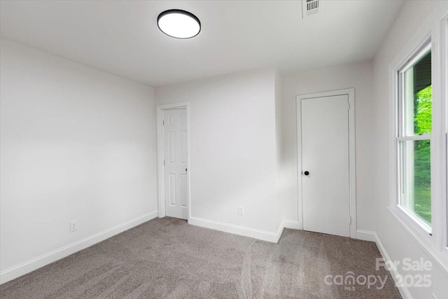 unfurnished room with plenty of natural light, visible vents, and carpet floors
