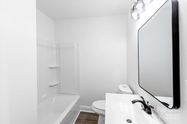 bathroom featuring tub / shower combination, wood finished floors, toilet, and baseboards