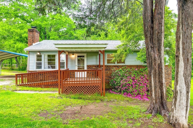 rear view of property featuring a chimney, a porch, brick siding, a shingled roof, and a detached carport