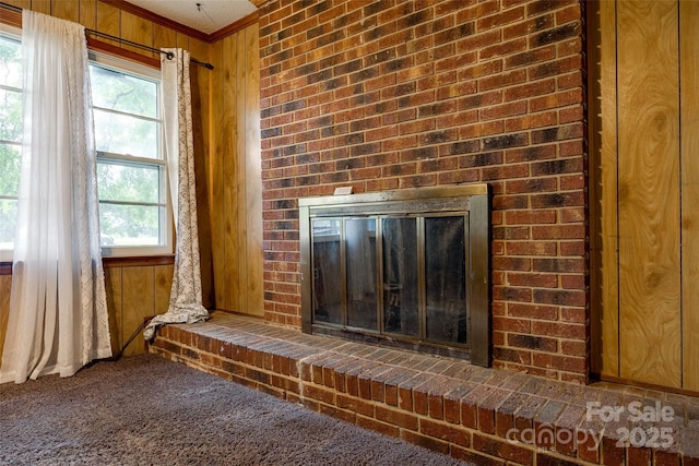 room details with carpet flooring, wooden walls, crown molding, and a brick fireplace