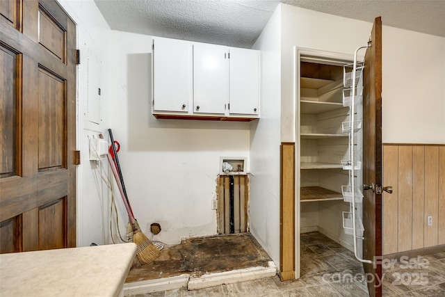 laundry area with hookup for a washing machine, laundry area, wood walls, a wainscoted wall, and a textured ceiling