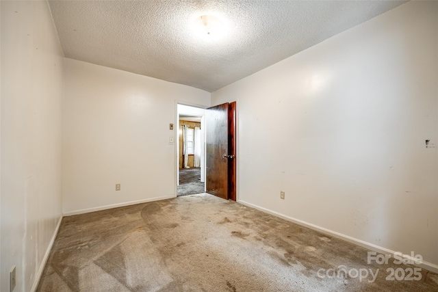 carpeted spare room featuring baseboards and a textured ceiling