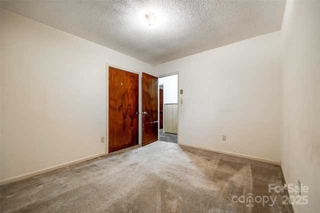 unfurnished room featuring baseboards, a textured ceiling, and carpet
