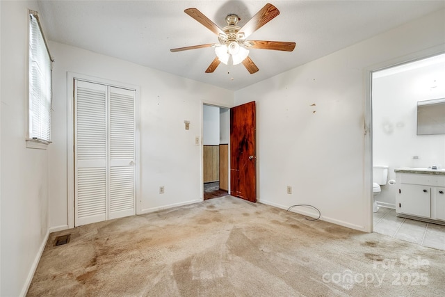 unfurnished bedroom featuring a closet, ceiling fan, visible vents, baseboards, and light colored carpet