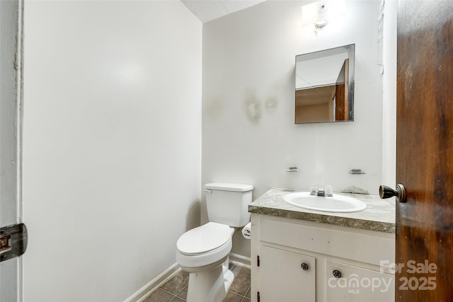 half bathroom featuring toilet, vanity, tile patterned floors, and baseboards