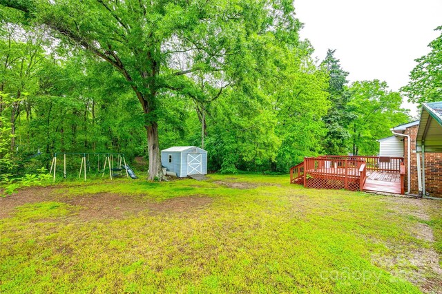 view of yard featuring a deck, a storage unit, an outdoor structure, and a playground