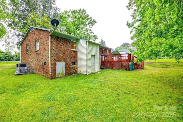 back of house featuring a lawn, a deck, central AC, and brick siding