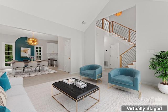 living area with high vaulted ceiling, stairs, visible vents, baseboards, and wood finished floors
