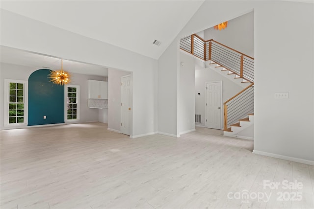 unfurnished living room with high vaulted ceiling, stairway, wood finished floors, and baseboards