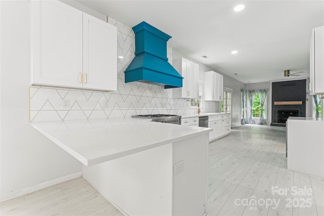 kitchen featuring ceiling fan, light wood-type flooring, custom exhaust hood, white cabinetry, and open floor plan