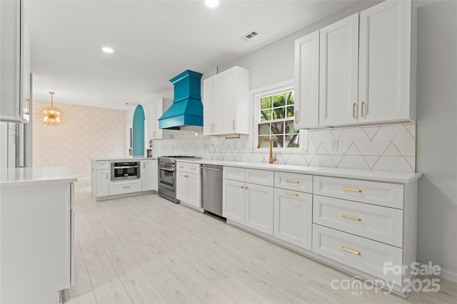 kitchen with visible vents, stainless steel appliances, custom exhaust hood, and light countertops