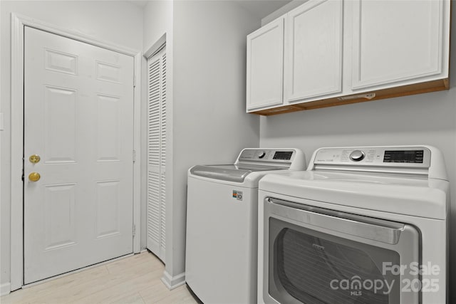 laundry room featuring light wood-style flooring, independent washer and dryer, and cabinet space