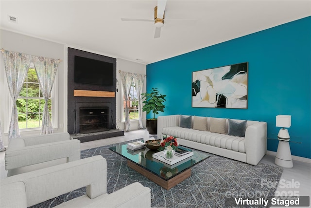 living room with a large fireplace, visible vents, ceiling fan, and baseboards