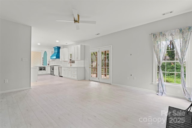 unfurnished living room with a ceiling fan, visible vents, light wood-style flooring, and a healthy amount of sunlight