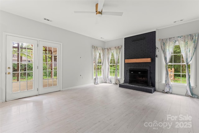 unfurnished living room featuring visible vents, ceiling fan, a fireplace, a wealth of natural light, and wood finished floors