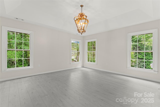 spare room with baseboards, visible vents, wood finished floors, and a chandelier